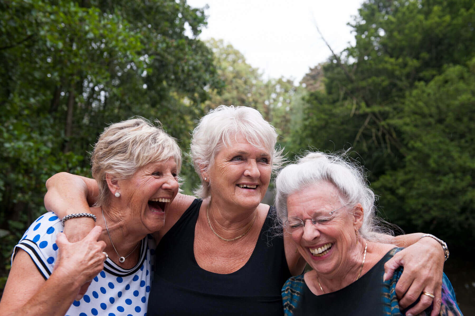 Drei Frauen liegen sich im Arm und lachen