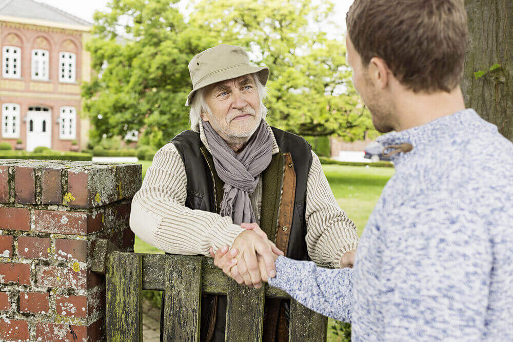 Zwei Männer am Gartenzaun reichen sich die Hand.